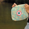 Hand Holding an Turquoise Cosmetic Pouch with Pink Evil Eye Embroidery 