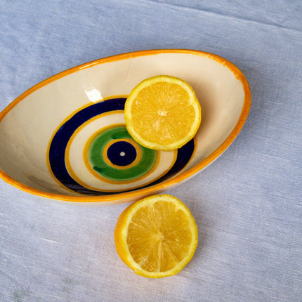 Casa Duniya's Hand-Painted Oval Yellow Evil Eye Bowls with Lemons against a White Linen Background
