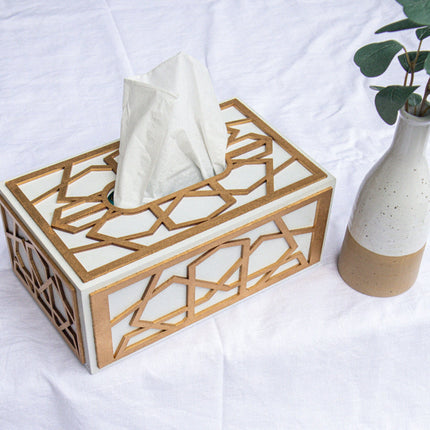 Casa Duniya's Hand-Painted White Gold Tissue Box Holder and Yahi White Beige Ceramic Holder with Leaves against a White Linen Table