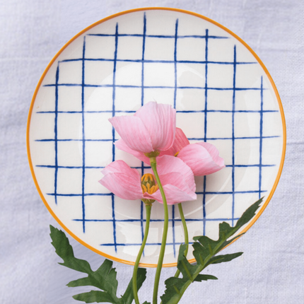 Casa Duniya's Blue and White Checkered Bone-China Zambila Dessert Plate with a Pink Flower and a White Linen Background
