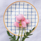 Casa Duniya's Blue and White Checkered Bone-China Zambila Dessert Plate with a Pink Flower and a White Linen Background